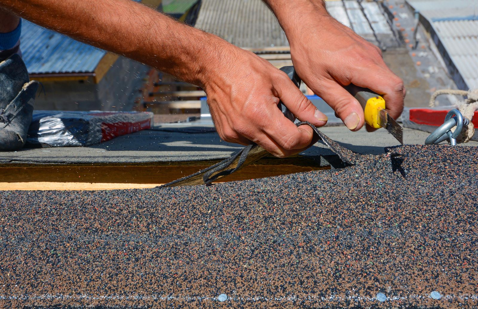 Roofer cutting shingles to fit at a valley
